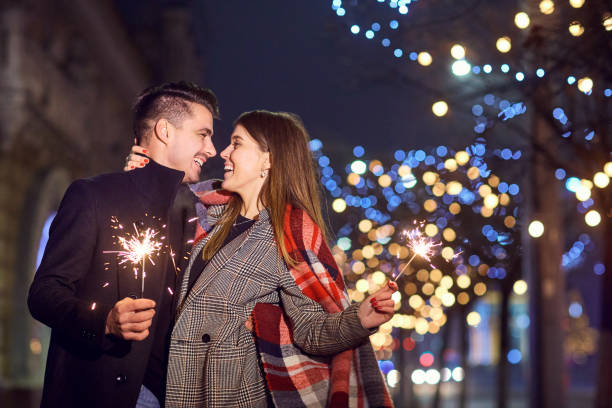 A young couple laughing with Bengal lights in the hands.
