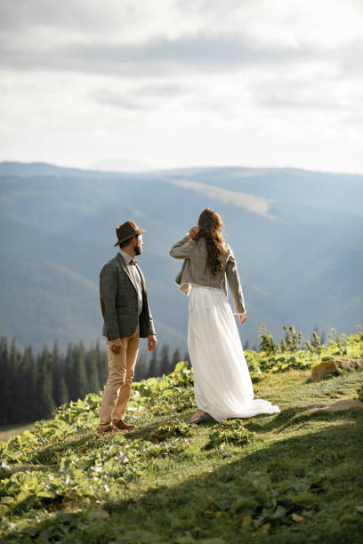 istock Newlyweds stand and look into distance in mountains. 893852428