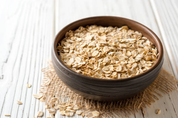 istock Oat flakes in ceramic bowl on white wooden table 893896502