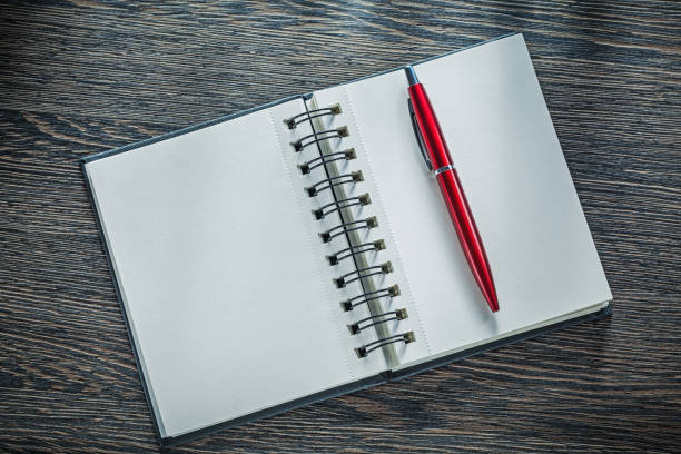 istock Opened notepad ballpoint pen on vintage wooden board 893899276