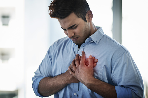 Shot of a young businessman suffering with chest pain at work