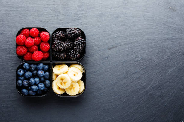 Small cups full of berries with wholewheat oats on dark stone surface
