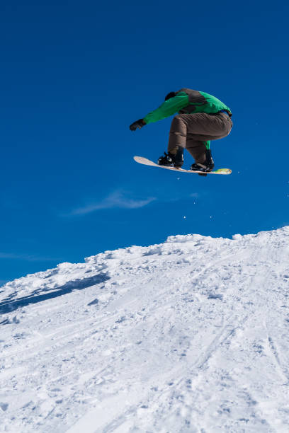istock Snowboarder jumping against blue sky 893963342
