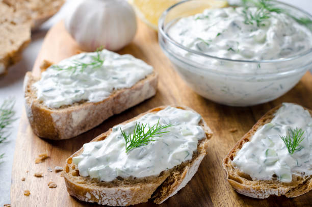 salsa tzatziki greca fatta in casa in una ciotola di vetro con pane a fette su una tavola di legno. primo piano, immagine orizzontale, messa a fuoco selettiva sul pane - mediterranean cuisine wood horizontal food and drink foto e immagini stock