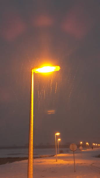 istock Snow flakes with orange lighted street light 893988056
