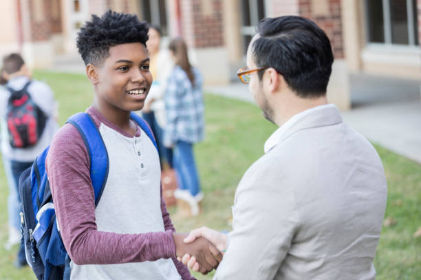 istock Friendly high school teacher greets new student 893988484
