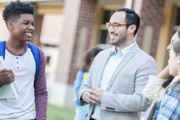 istock Hispanic male teacher visits with students before class 893988510