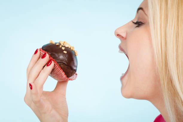 istock Woman holding chocolate cupcake about to bite 893988686