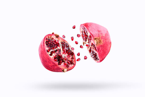 istock Pomegranate in flight burst on a white background, isolated. Cut half pomegranate flying in the air. Pomegranate fruit explosion 893988930