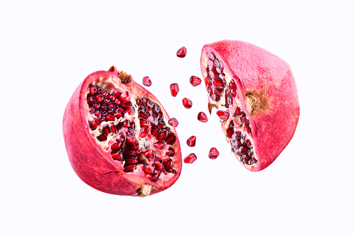 Pomegranate in flight burst on a white background, isolated. Cut half pomegranate flying in the air. Pomegranate fruit explosion.