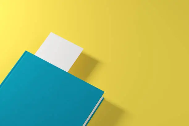 Closed green book with a white bookmark is lying on a yellow surface. Concept of advertising. 3d rendering mock up