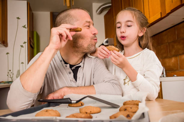 istock Father and Elementary Aged Girl Tasting a Home Made Cookies Together 894037200