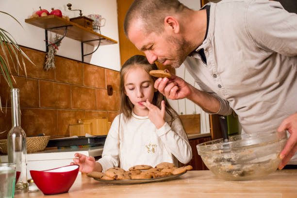 istock Father and Elementary Aged Girl Tasting a Home Made Cookies Together 894037210