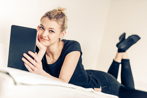 Teenage Girl Student Using Digital Tablet in Bed