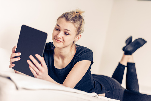 Teenage Girl Student Using Digital Tablet in Bed