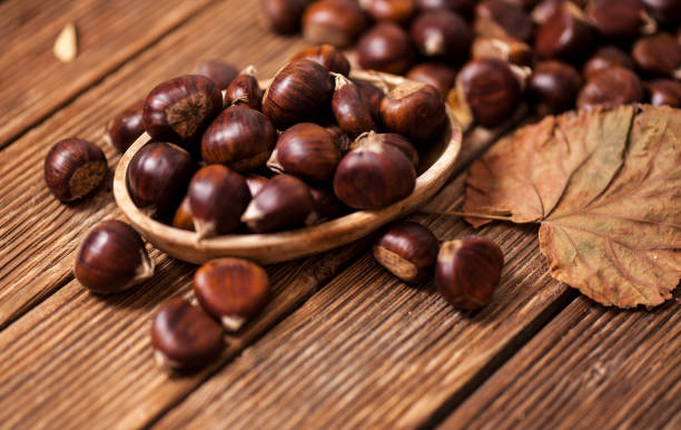 reife kastanien in einer pfanne auf alten holztisch hautnah mit textfreiraum. gebratene kastanien für christmas'n - chestnut stock-fotos und bilder