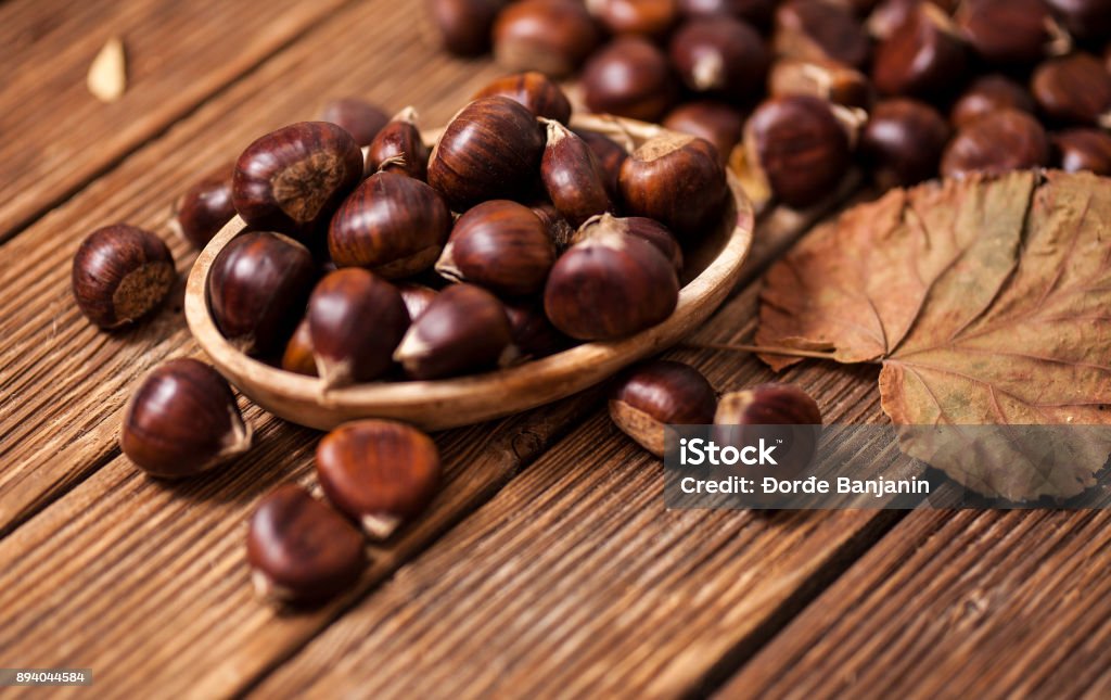 Ripe chestnuts in a frying pan on old wooden table close up with copy space. Roasted Chestnuts for Christmas'n Chestnut Tree Stock Photo