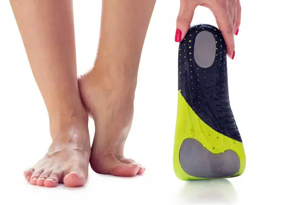 female feet stand on their toes and orthopedic insole in the hand
