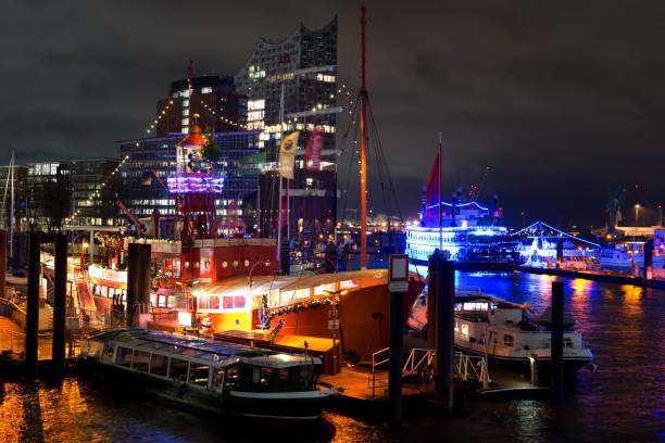 Hamburg, Germany - 12/09/2017: Illuminated ships at St. Pauli piers at night, in the background Hamburgs new landmark, the concert hall Elbphilharmonie.