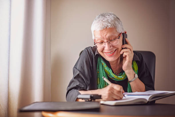 istock Senior older woman writing down phone orders 894074176