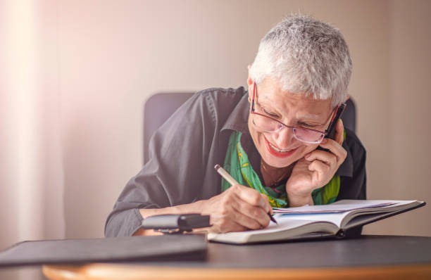 istock Senior older woman writing down phone orders 894074190