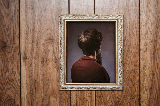 Bizarre Backwards Vintage Portrait A picture frame hangs on a wall with an ornate frame and retro style, the person posing in the portrait facing the wrong direction, only the back of their head and body visible.  Wood paneling wall; horizontal with copy space. obscured face photos stock pictures, royalty-free photos & images