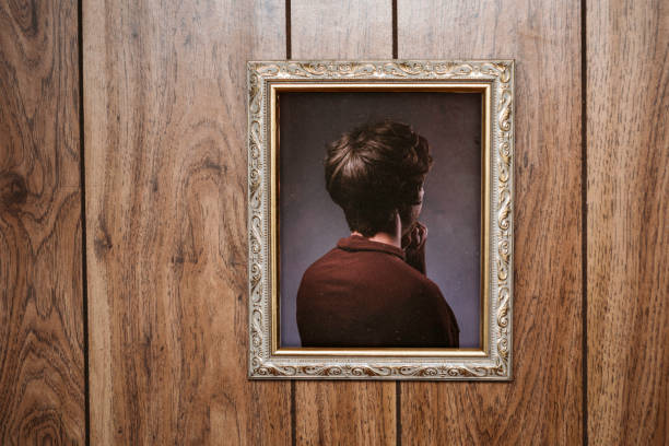 Bizarre Backwards Vintage Portrait A picture frame hangs on a wall with an ornate frame and retro style, the person posing in the portrait facing the wrong direction, only the back of their head and body visible.  Wood paneling wall; horizontal with copy space. wood paneling retro stock pictures, royalty-free photos & images