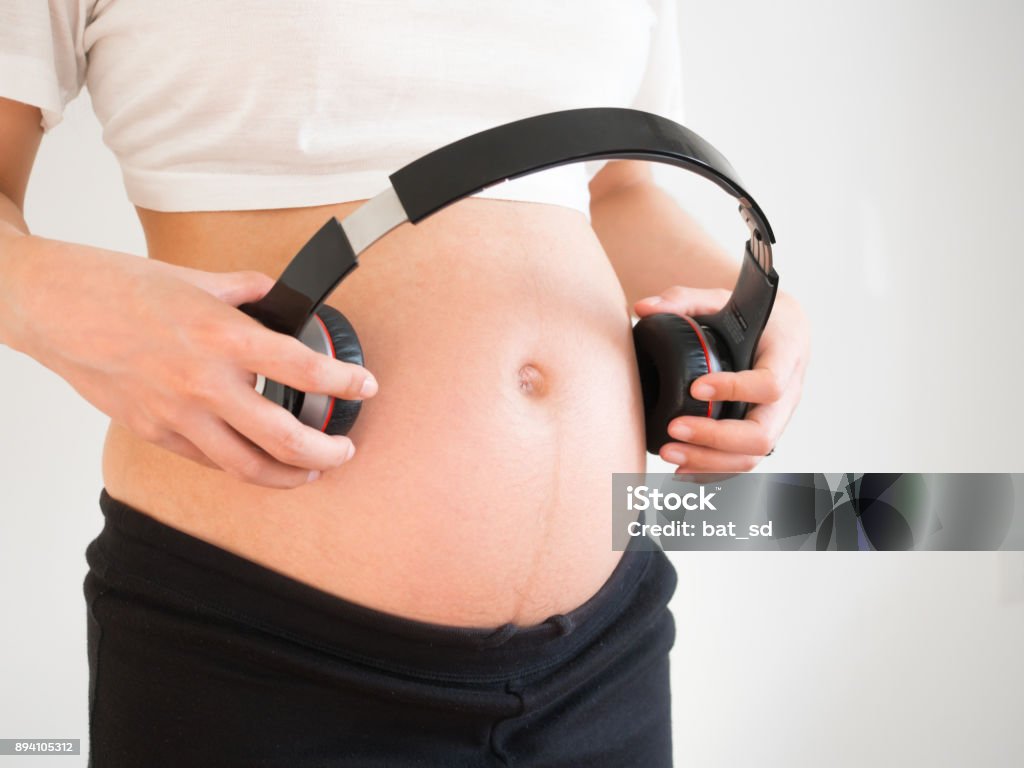Pregnant Woman Holding Headphones On Her Belly Music For Baby Concept  Pregnancy And Music Stock Photo - Download Image Now - iStock