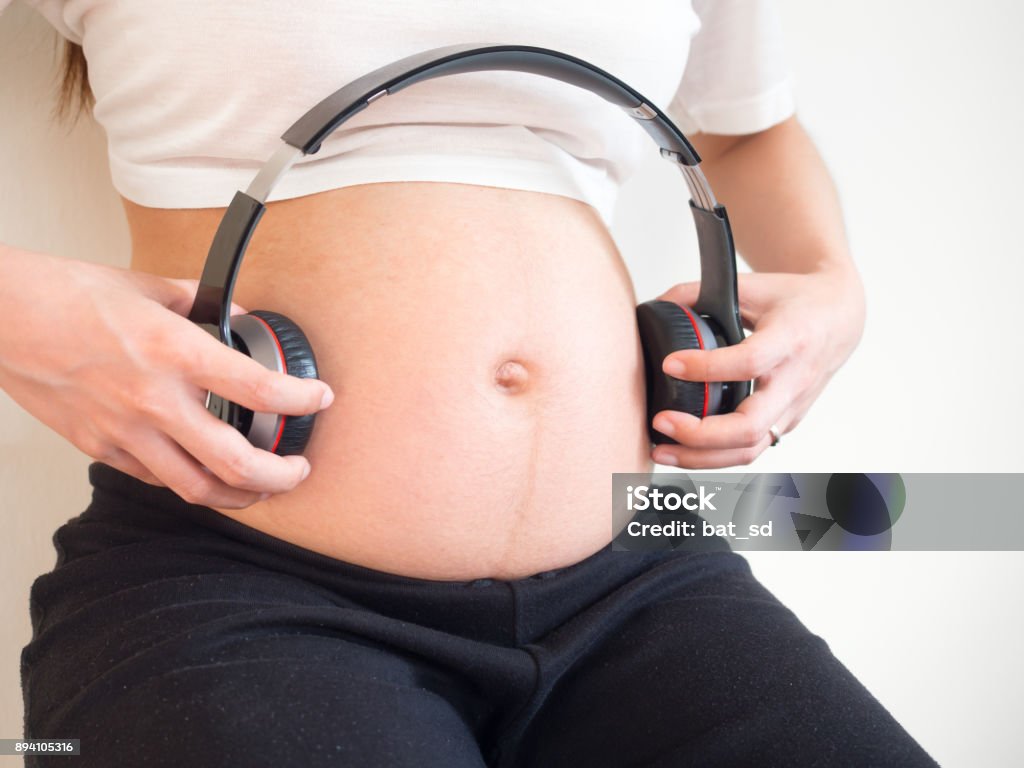 Pregnant Woman Holding Headphones On Her Belly Music For Baby Concept  Pregnancy And Music Stock Photo - Download Image Now - iStock