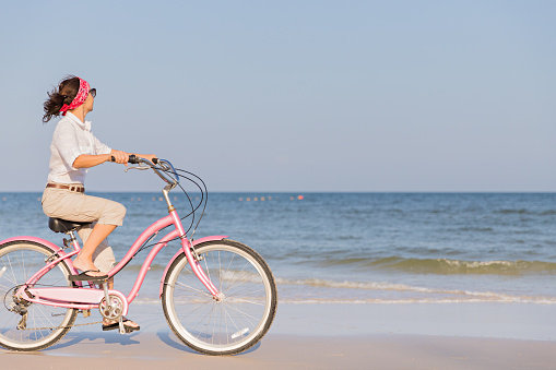Happy woman riding bike on beach