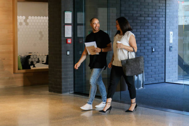 Duas pessoas a pé através de um lobby de escritório - foto de acervo