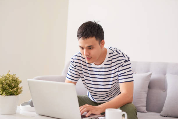 istock Asian man sitting on couch with laptop 894162092