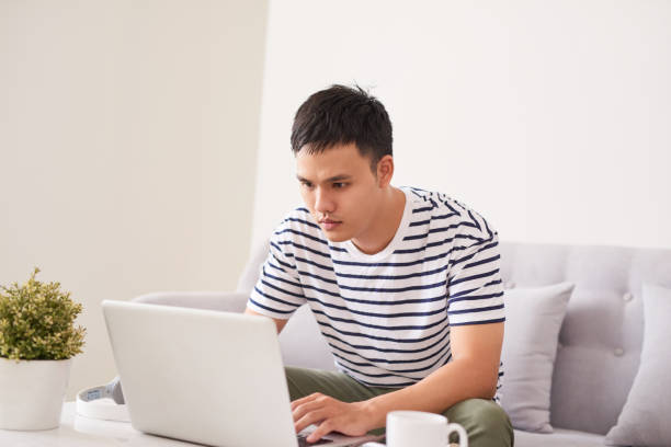 istock Young asian man at home on sofa using a laptop. 894167840