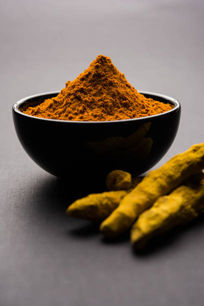 istock Turmeric powder in ceramic bowl with raw dried turmeric over plain background 894168906