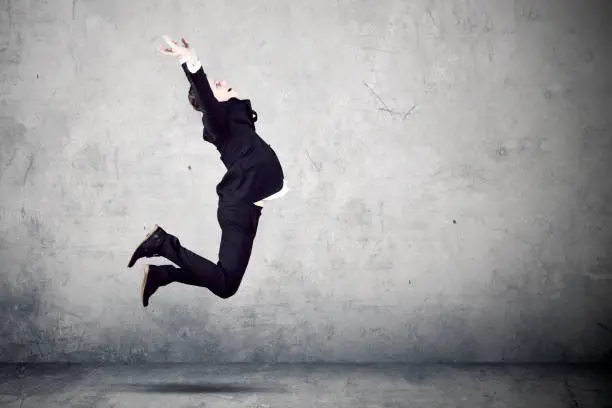 Image of young businessman wearing formal suit while jumping to celebrate his success