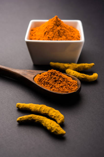 istock Turmeric powder in ceramic bowl with raw dried turmeric over plain background 894186738