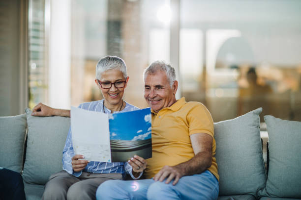 Smiling mature couple relaxing on sofa at patio and reading magazine.