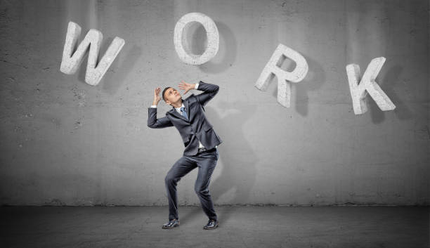 istock A scared businessman hides under large concrete letters making a word Work above him on a grey background 894203782