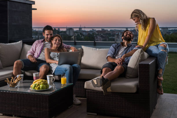 istock Two happy couples relaxing on sofa at penthouse balcony. 894206396