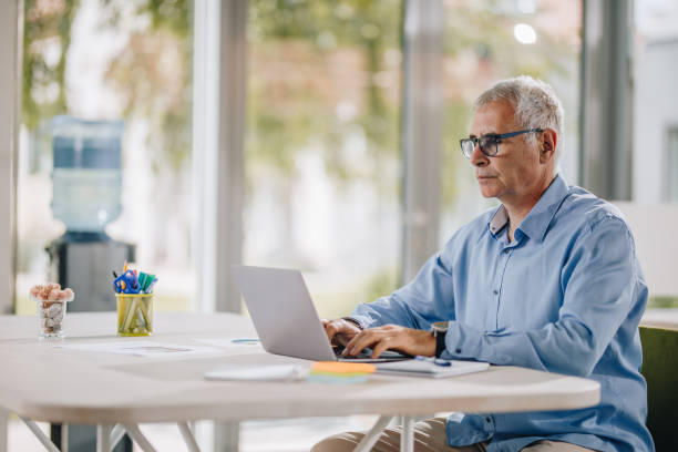 istock Mature businessman typing an e-mail on laptop in the office. 894299580
