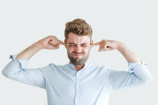Stressed Young Man Stopping Ears with Fingers Portrait of annoyed handsome young man with closed eyes stopping his ears with fingers. Businessman getting too much news and feeling high stress. Stressful job and negative emotions concept man closing ears photos stock pictures, royalty-free photos & images