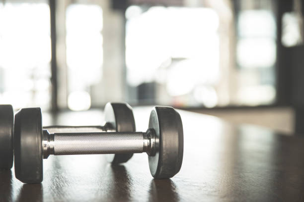 istock Dumbbells on wooden table in Gym background 894318892