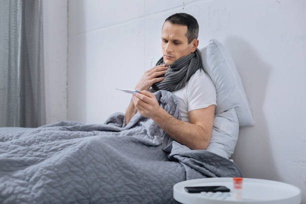 istock Sick male person looking at thermometer 894322264