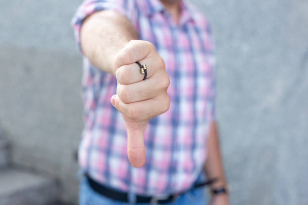 istock Upset man showing thumb-down sign to dislike 894337944