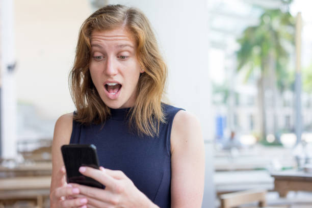 istock Surprised Young Woman Using Smartphone Outdoors 894340870