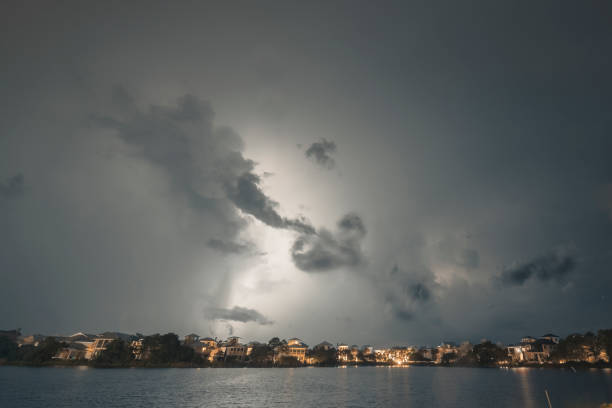 Massive Hurrican Harvey Storm clouds with lightning at night. A spinoff band of storms from Hurricane Harvey produces an impressive light show at night with large lightning revealing turbulent clouds as they pass over a small beachside community and a lake in the foreground. hurrican stock pictures, royalty-free photos & images