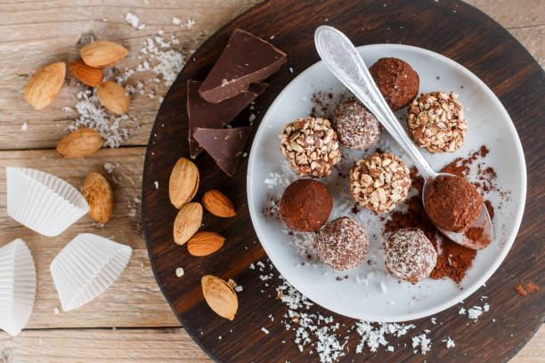 istock Prepare assorted dark chocolate truffles with cocoa powder, coconut and chopped almonds closeup. Homemade candy. Selective focus 894341838