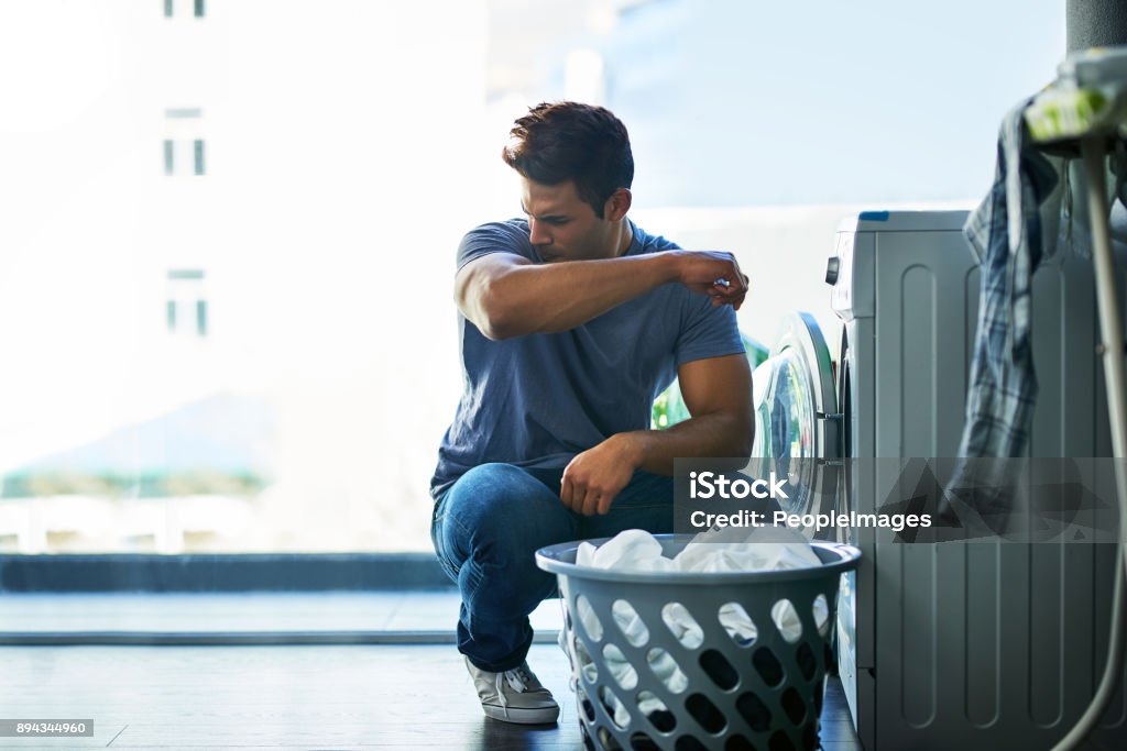That doesn't smell good, this needs to be washed too Shot of a young man doing household chores Unpleasant Smell Stock Photo