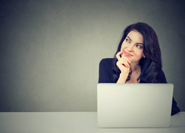 young business woman thinking daydreaming sitting at desk with laptop computer young business woman thinking daydreaming sitting at desk with laptop computer Distracted stock pictures, royalty-free photos & images