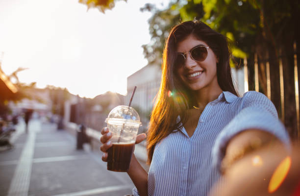 красивая женщина пьет кофе и делает селфи в городе - vacations photographing brown hair 30s стоковые фото и изображения